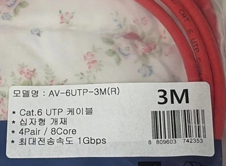 빨간 CAT.6 랜선 포장 스티커에 Cat.6 UTP 케이블, 십자형 개재, 4Pair / 8Core, 최대전송속도 1Gbps가 적혀 있고 선 겉면에 CAT 6 UTP 인쇄가 보이는 사진