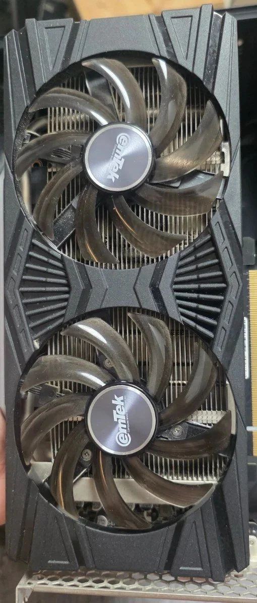 팬 두 개가 달린 그래픽카드 앞면, 팬 날개 가장자리에 먼지가 앉고 그 아래로 방열판 핀이 보이는 모습